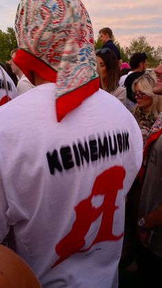 a group of people standing next to each other wearing white shirts and red caps with the words keineemburg on them