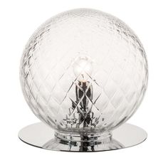 a clear glass table lamp sitting on top of a metal base with a light bulb in the center