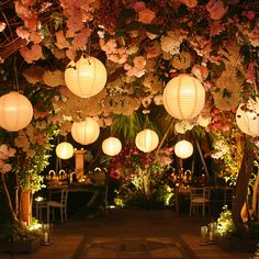 an outdoor wedding with paper lanterns hanging from the ceiling and flowers all over the place