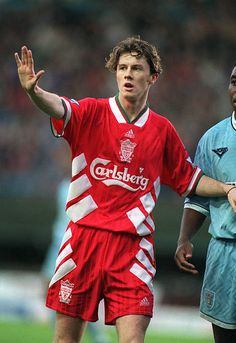 two young men playing soccer on a field with one holding his hand out to the side