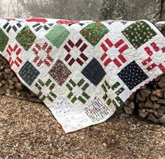 a patchwork quilt on top of logs in the woods