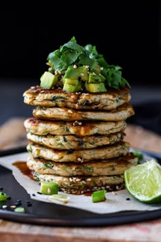 a stack of pancakes with avocado, cilantro and lime on top