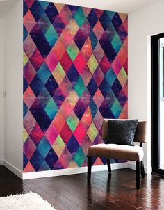 a chair sitting in front of a wall covered in multicolored geometric art pieces