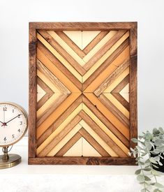 a clock sitting on top of a table next to a wooden frame with geometric designs