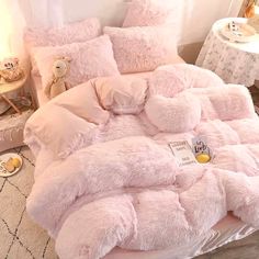 a bed with pink comforters and pillows in a child's bedroom, next to a teddy bear