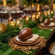 a football themed table setting with greenery and gold chargers on the plates, along with candles