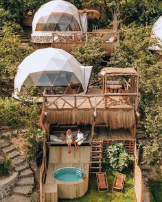 two people sitting on top of a wooden deck next to a hot tub in the middle of trees