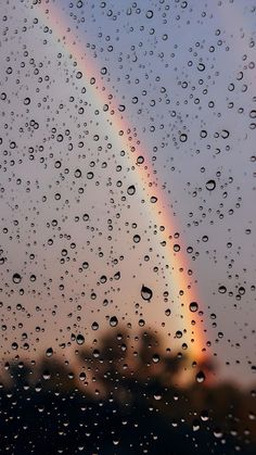 rain drops on the window with a rainbow in the back ground and sky behind it