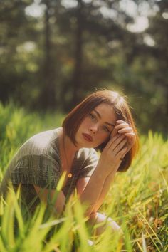 a woman sitting in the grass with her hands on her head