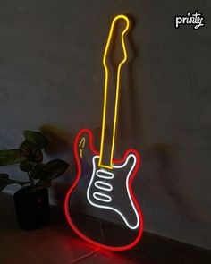 an electric guitar neon sign on a wall next to a potted plant