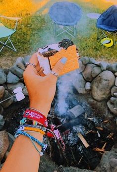 a person holding up a piece of food over a fire