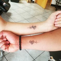 two people with matching tattoos on their arms, one has a heart and the other has a heartbeat