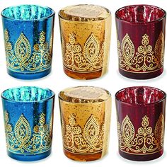 four different colored glass candle holders with gold designs on the sides and one is blue