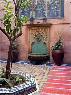 an outdoor fountain surrounded by potted plants