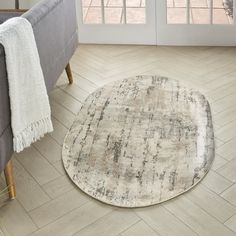 a living room with a gray couch and white rug on the floor next to a window