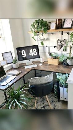 a desk with a laptop, computer monitor and plants on it in front of a window