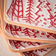 four red and white plates with trees painted on them are stacked in a pyramid shape