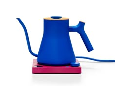 a blue tea kettle sitting on top of a pink box with a cord attached to it