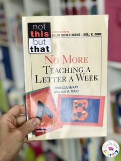 a person holding up a book in front of a store shelf with the title, not this but that no more teaching a letter a week