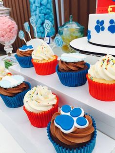 cupcakes with frosting and paw prints are on display at a dog themed birthday party