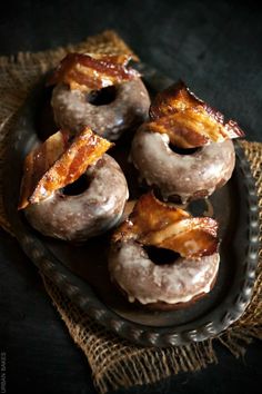 doughnuts with bacon are on a black plate and burlied cloth in the background