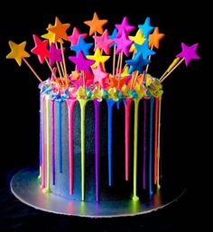 there is a cake decorated with stars and rainbow icing on the top, along with candles