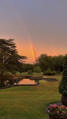 a rainbow is seen in the sky over a pond