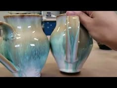 two handmade vases sitting on top of a wooden table next to each other