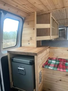 the interior of a small camper with wood paneling and cabinets, including a stove