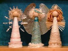 three angel figurines are on display in a glass case with blue velvet behind them