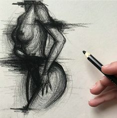 a person holding a pencil in front of a drawing of a naked woman on paper