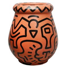 an orange vase with black designs on it