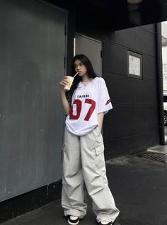 For a laid-back yet edgy streetwear look, this oversized jersey paired with wide-leg cargo pants nails the perfect balance of comfort and style. The bold red print on the jersey contrasts well with the neutral pants, making the whole outfit pop. With chunky sneakers to complete the vibe, this look is ideal for a chill day out or hitting the streets with confidence! Boyish Outfit For Women, Tomboy Fits Aesthetic, Boyish Outfits Aesthetic, Casual Boyish Outfits, Baggy Fits Aesthetic, Boyish Fits, Girls Baggy Outfits, Boyish Outfit, Baggy Aesthetic