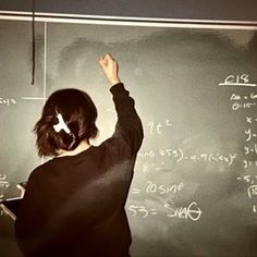 a woman writing on a blackboard with chalk