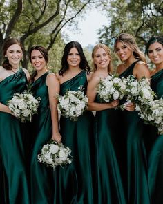 a group of women standing next to each other wearing green dresses and holding bouquets