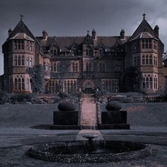 a large building with a fountain in front of it on a cloudy day at night