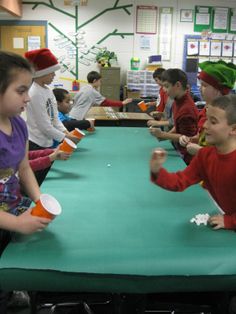 several children sitting at a table with cups in front of them and one child holding a paper cup