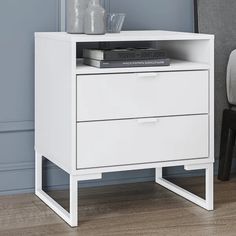 a white night stand with two drawers and a book on it's top shelf