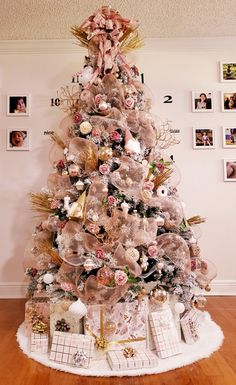 a white christmas tree with pink and gold ornaments on it's top, surrounded by photos