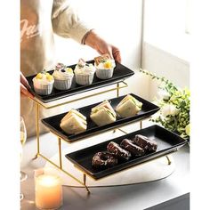 three tiered trays filled with pastries on top of a table next to a candle