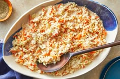 a bowl filled with rice and carrots on top of a table next to two blue plates