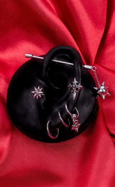 two pairs of black jewelry sitting on top of a red cloth