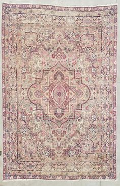 an antique persian rug with pink and blue colors on the center, surrounded by floral designs