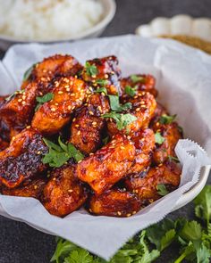 chicken wings with sesame seeds and cilantro in a white bowl on a table