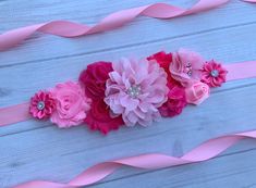 pink flowers and ribbons on a white wooden surface