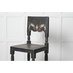 an old wooden chair with a butterfly painted on it's back and seat, against a white wall