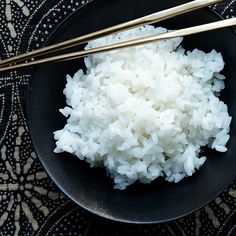 white rice and chopsticks in a black bowl