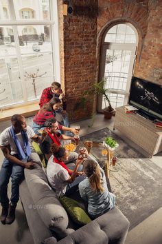 a group of people sitting on top of a couch in a living room next to a window