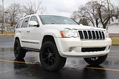 a white jeep parked in a parking lot on a rainy day with no one around