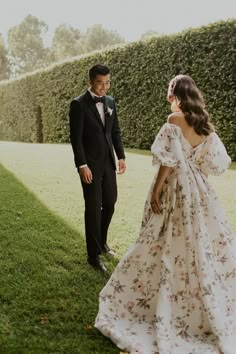 a man in a suit and tie standing next to a woman in a floral dress